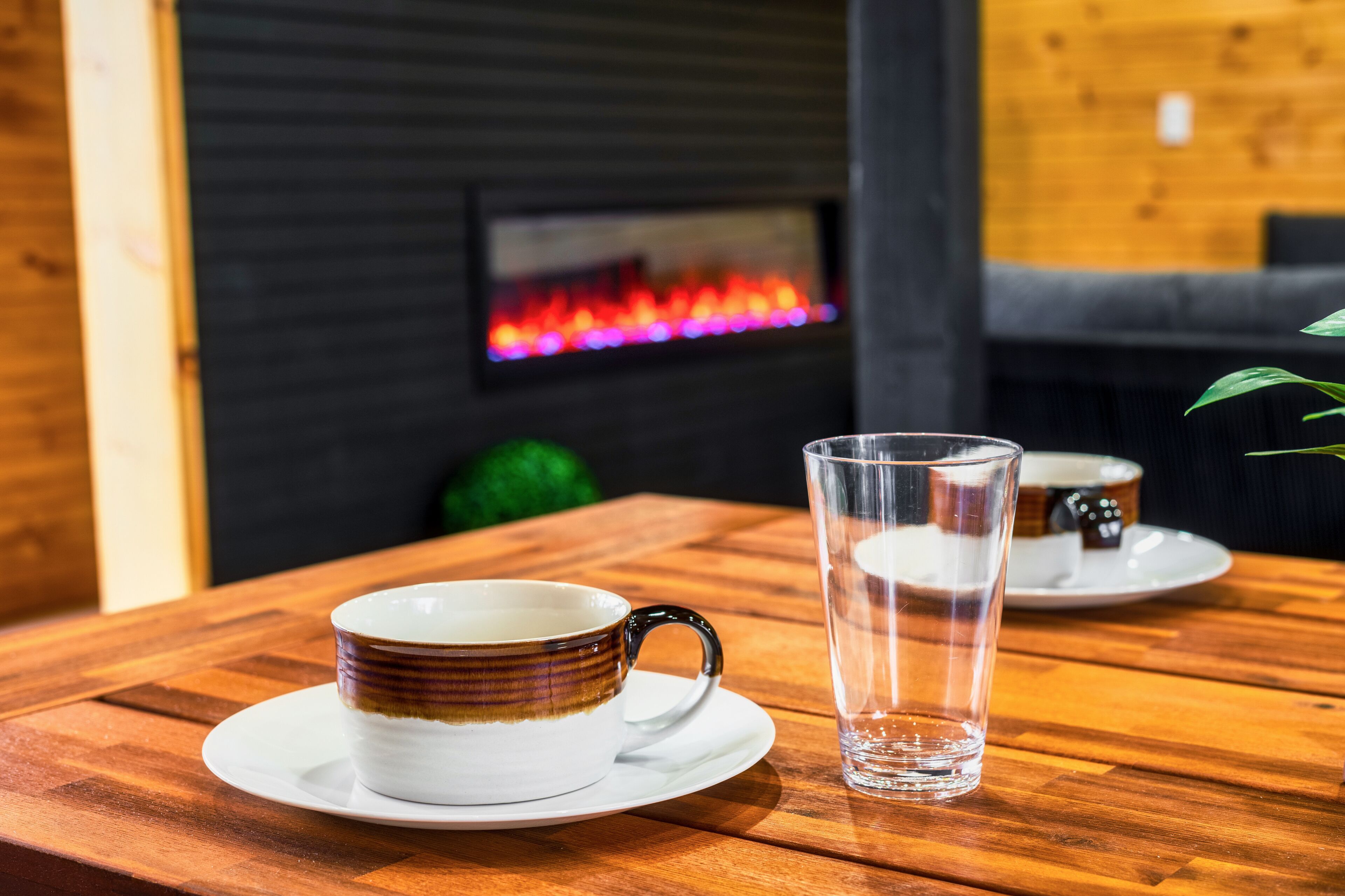 Une table en bois, une tasse en céramique et un verre transparent.