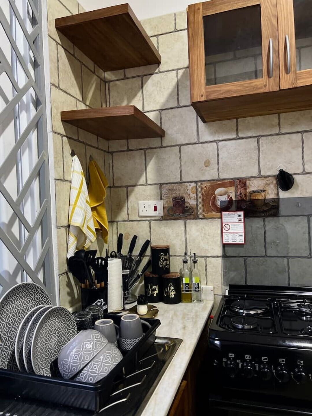 A kitchen with a stove, wooden cabinets, and a tiled backsplash.