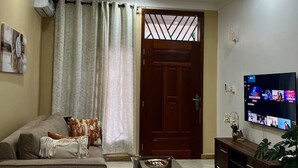 A living room with a sofa, a glass coffee table, a TV, and a wooden cabinet. - TiniTara Cozy Home (Dar es Salaam, Tanzania)