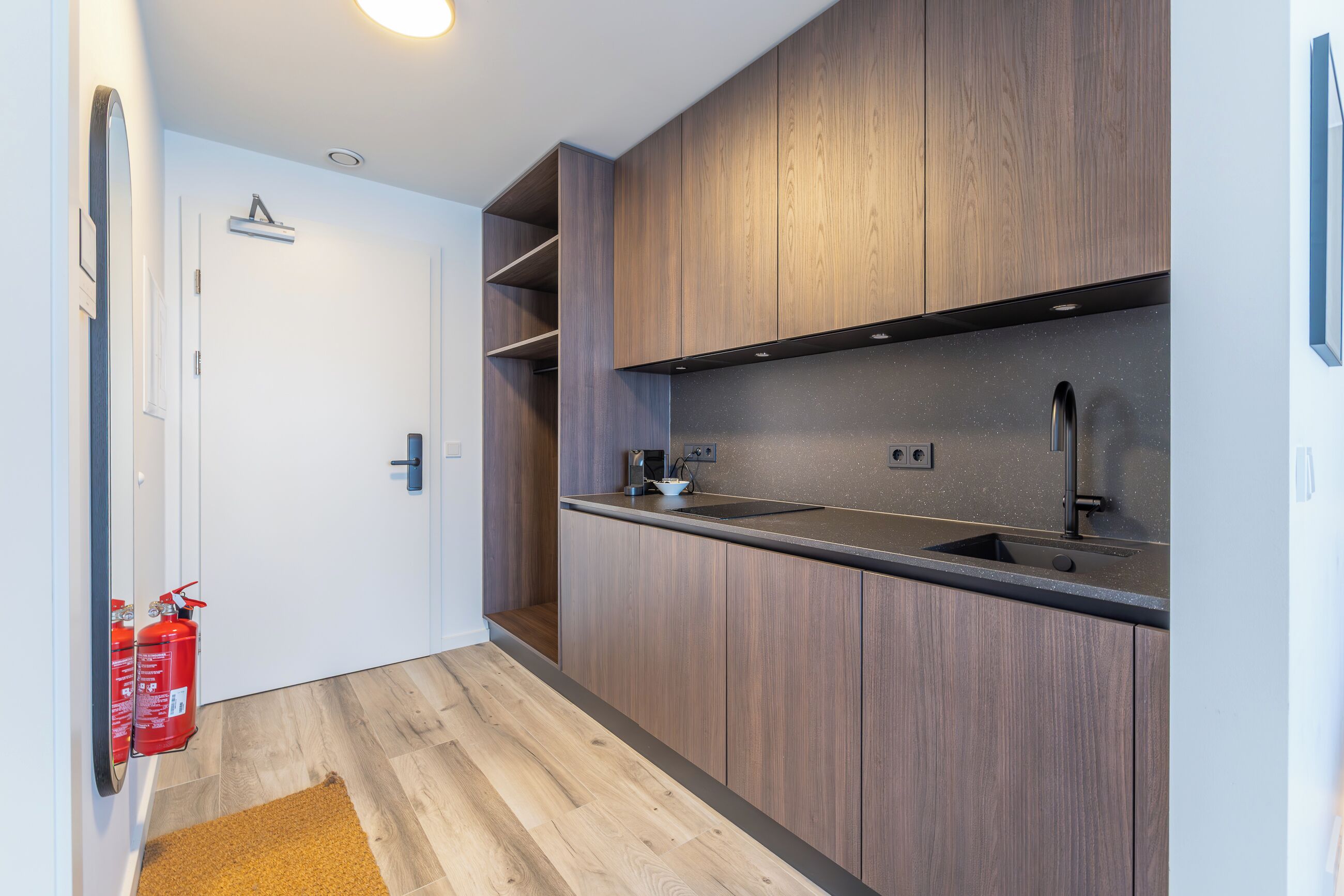 A modern kitchen with wooden cabinets, a black countertop, and a stainless steel sink.