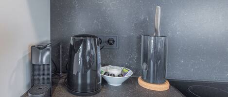 A kitchen with a coffee maker, a kettle, and a toaster on a granite countertop.