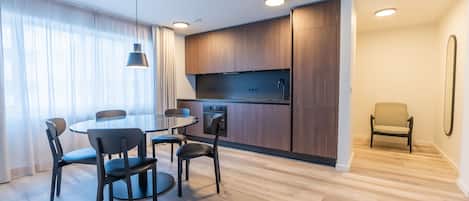 Una cocina moderna con armarios de madera, una mesa redonda con sillas y una lámpara colgante.