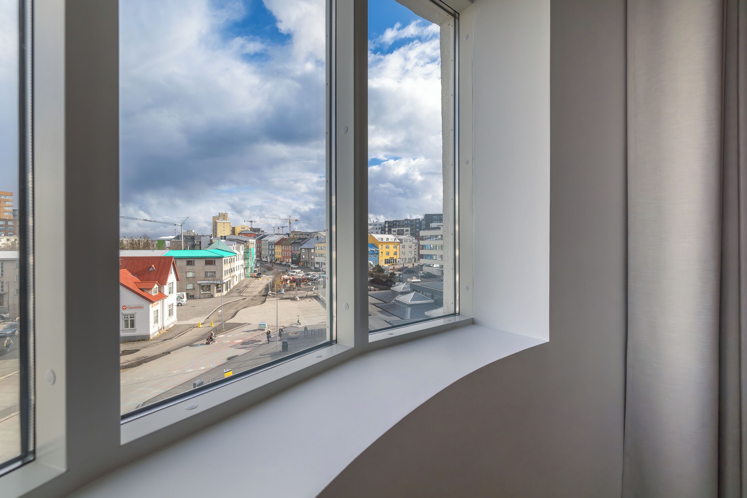 Uitzicht vanuit een raam op een stadsgezicht met gebouwen en een bouwplaats.