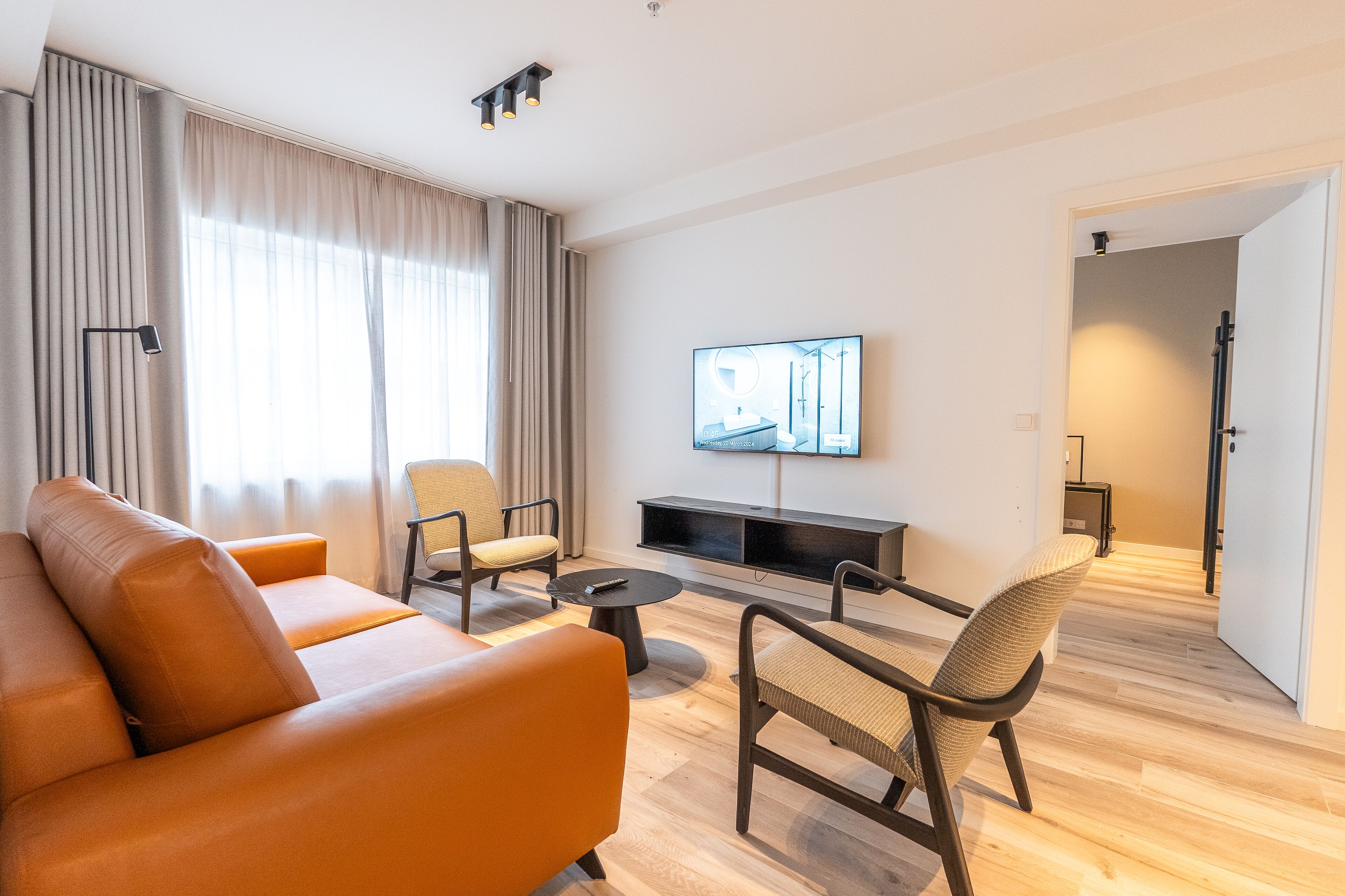A modern living room with a sofa, chairs, a coffee table, and a TV.