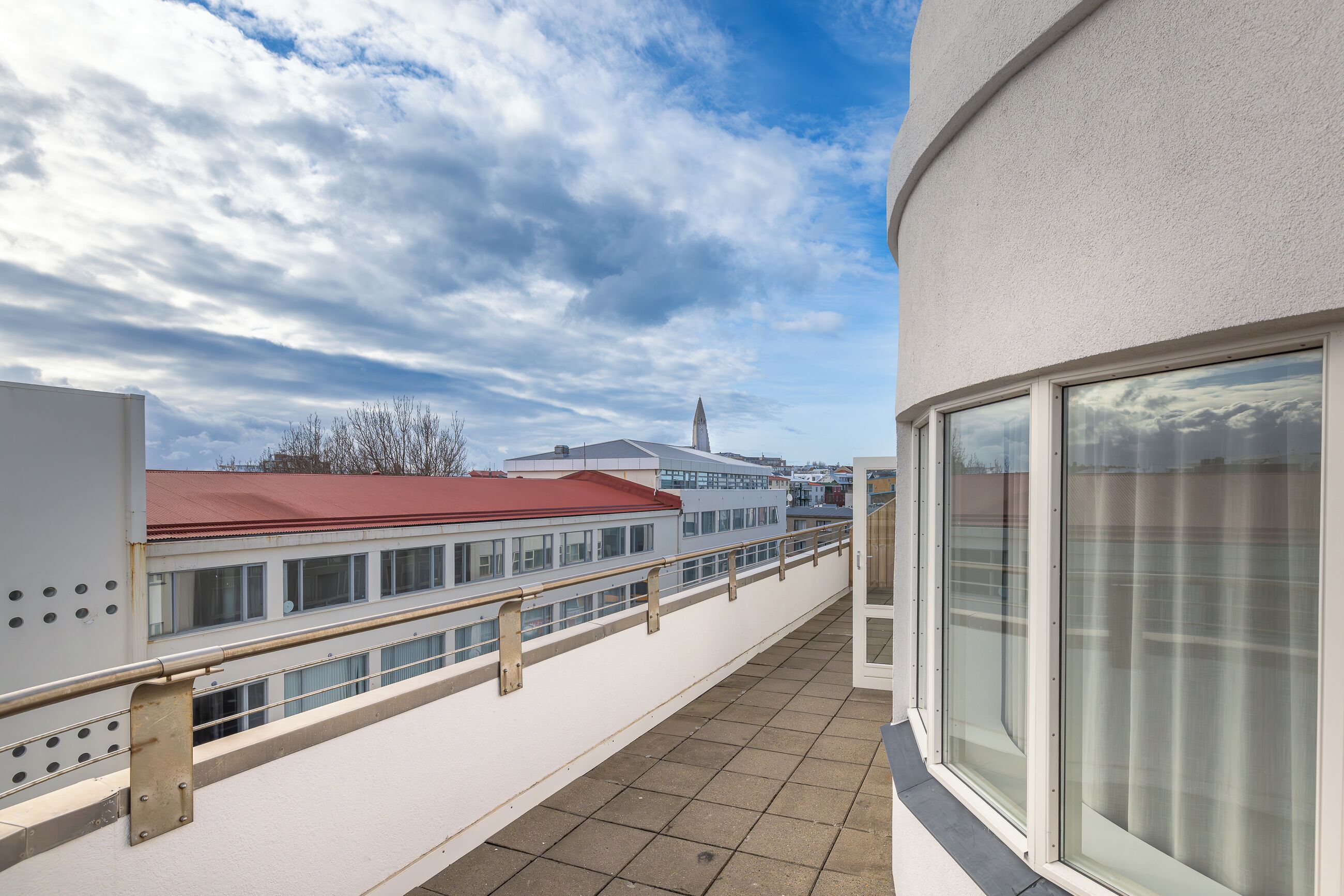 A balcony with a view of a building with a red roof and a tower.
