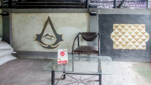 Une table en verre sur laquelle se trouve une boîte blanche, une chaise et un mur orné d’un logo et d’un motif en losange.