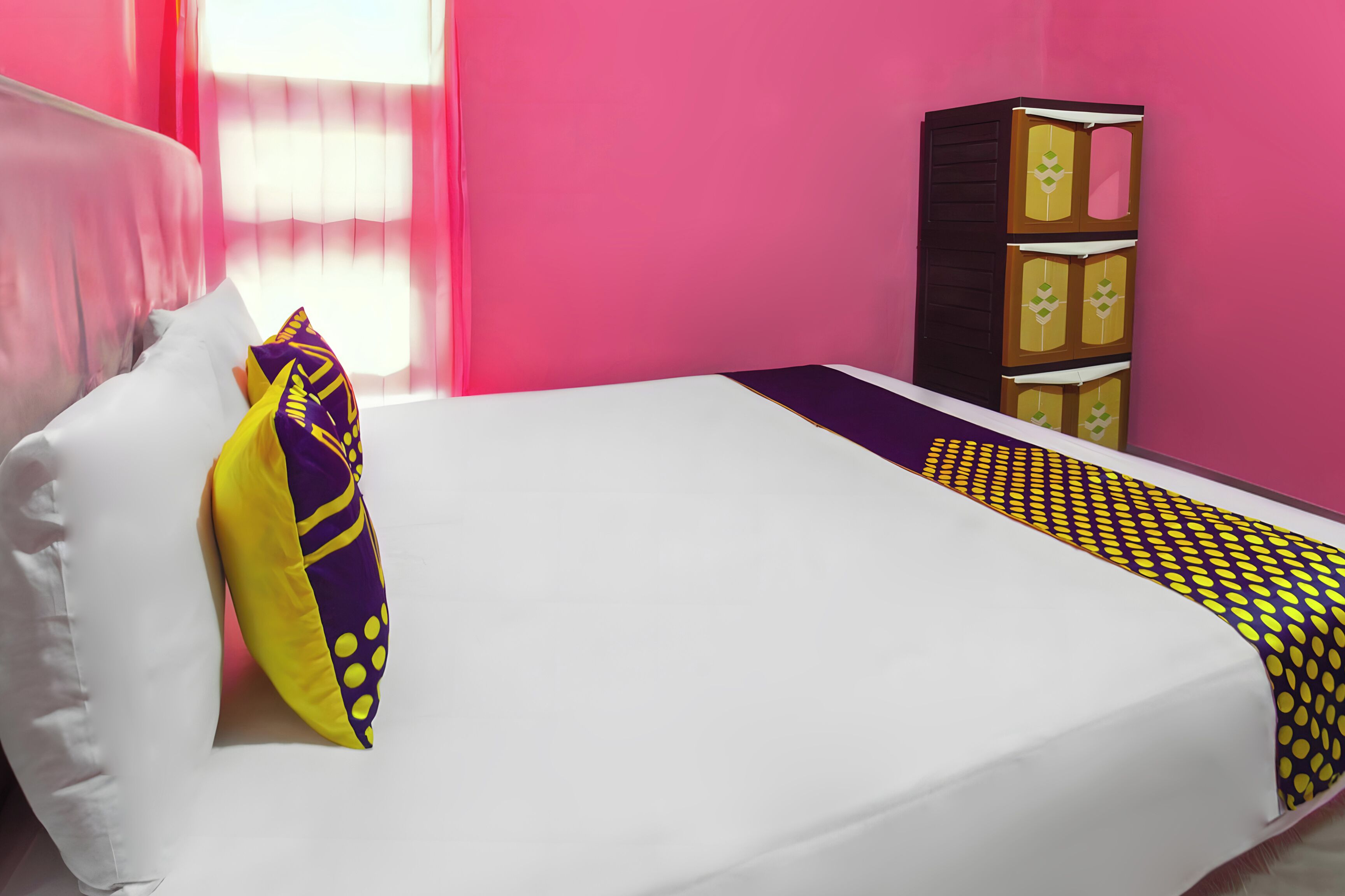 A bed with a white mattress, a purple and yellow pillow, and a patterned blanket.