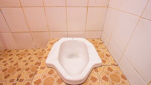 Des toilettes avec un abattant blanc et un carrelage décoré.