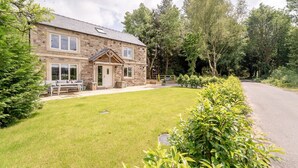 A stone house with a well-maintained lawn and a paved driveway. - Bramley Brook Cottage 5 star Luxury (Whalley)