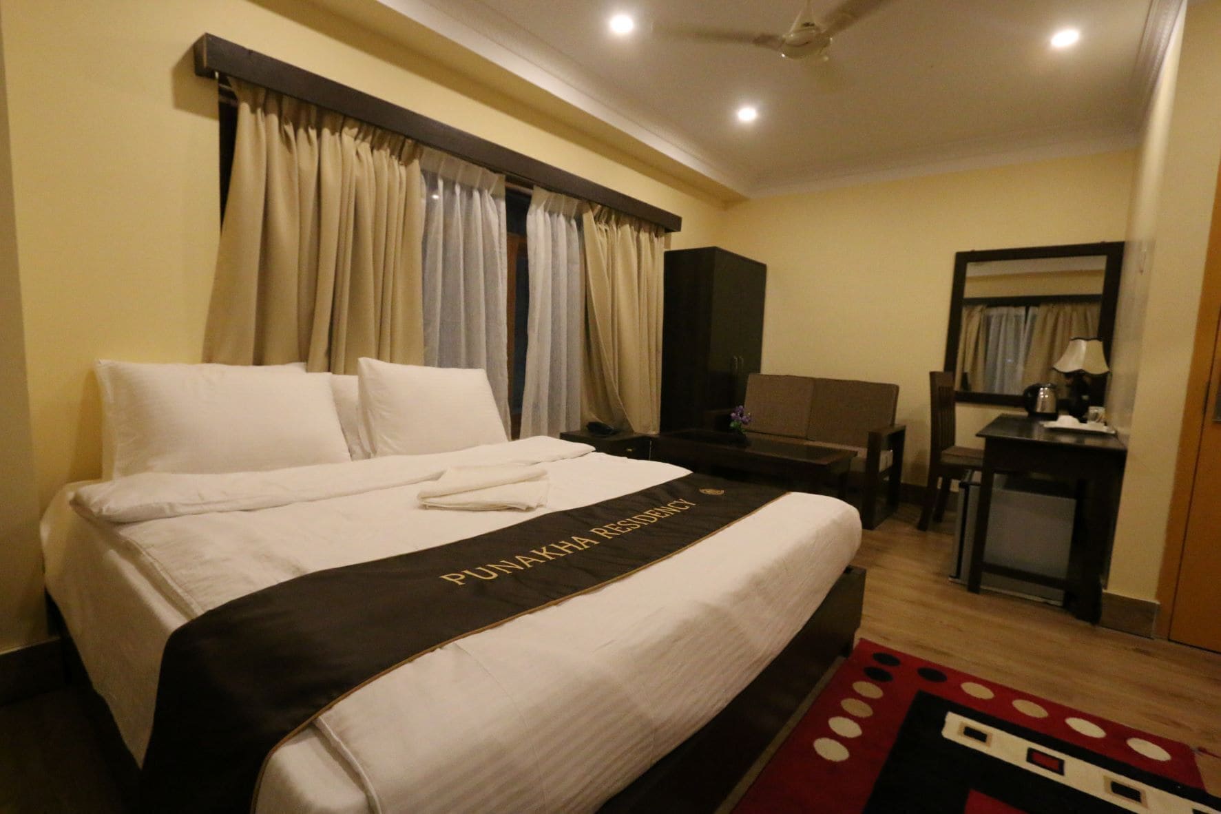 Una habitación de hotel con una cama, un escritorio, una silla y una pequeña mesa.