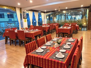 A restaurant with multiple tables set for dining, featuring traditional decor and a view through the window. - Punakha Residency Hotel (Punakha)