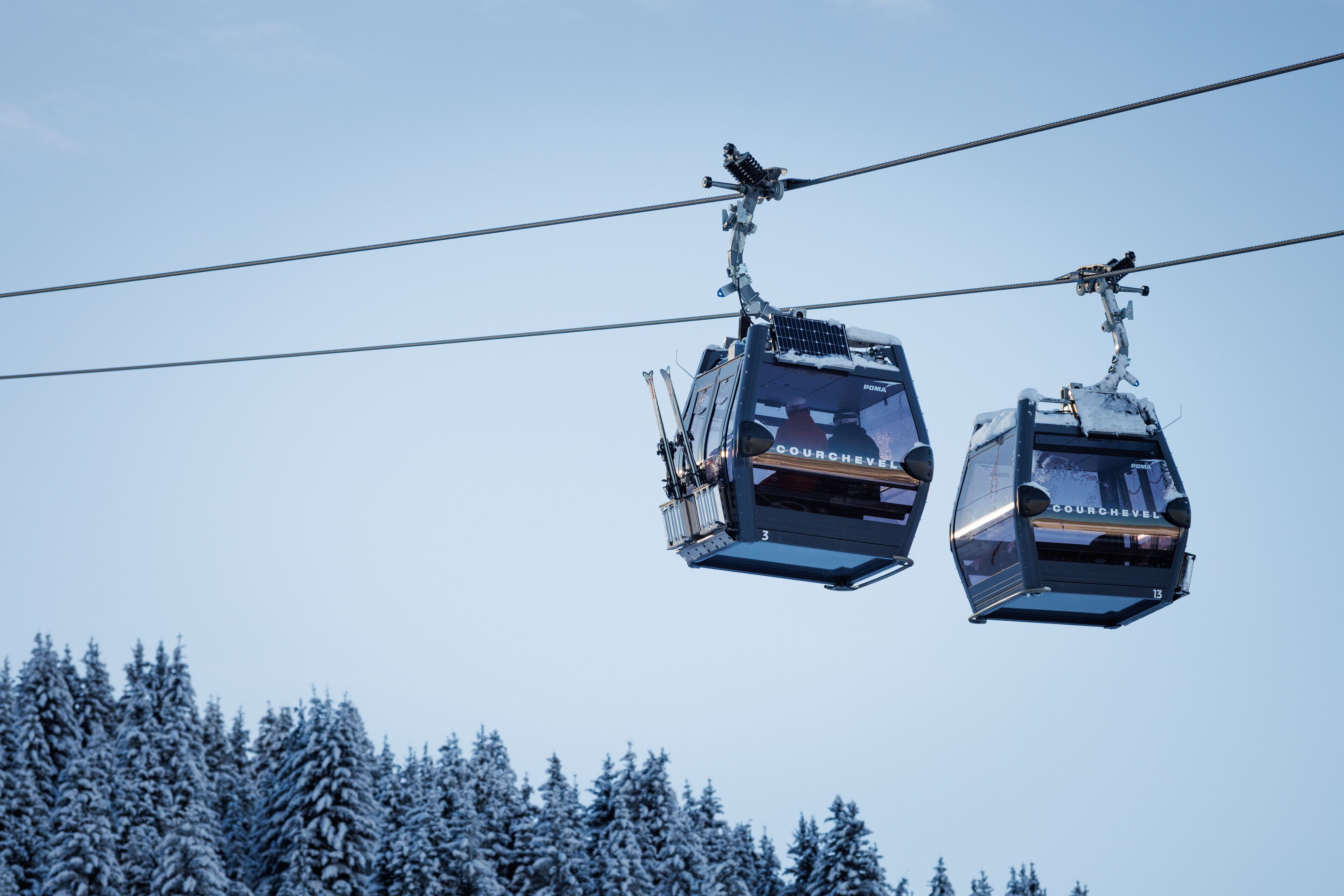 Two cable cars suspended by cables against a clear sky.