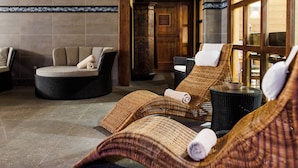Ein Wellnessbereich mit Liegestühlen, einer Massageliege und einem großen Fenster für natürliches Licht.