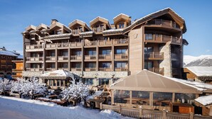 Ein mehrstöckiges Hotel mit traditioneller Holzfassade, Balkonen und verschneitem Gelände.