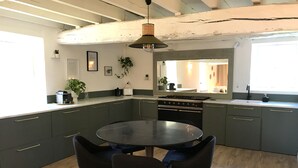 Une cuisine moderne avec des meubles de couleur sombre, une table ronde et quatre chaises.