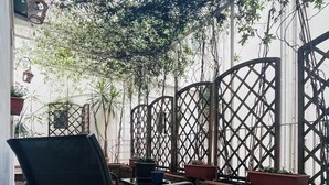 A patio area with potted plants, a black chair, and a lattice fence. - Apartment Luxury Via Chiaia  (Napoli)