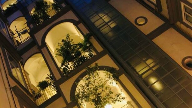 A multi-level building with balconies and arched windows, featuring a warm interior lighting. - Apartment Luxury Via Chiaia  (Napoli)