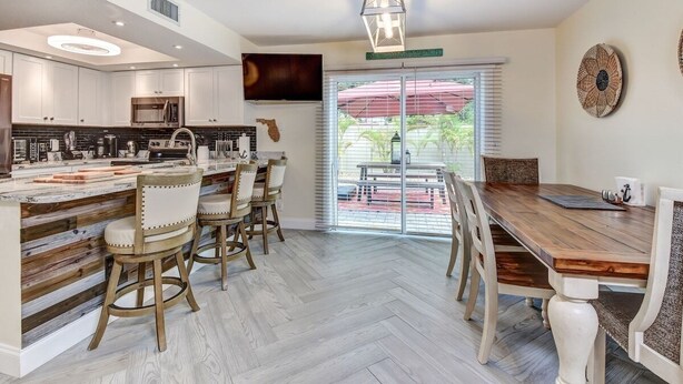 Una cocina moderna con una isla central, sillas de madera y una mesa de comedor con sillas.