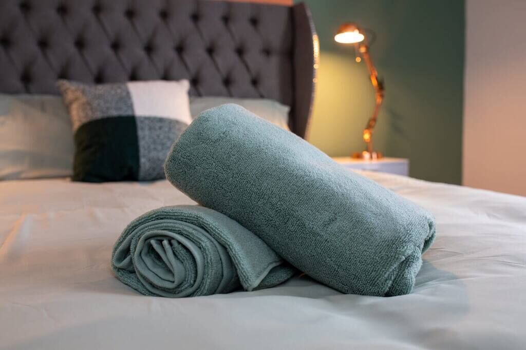 A neatly made bed with a folded towel and a lamp on the side.