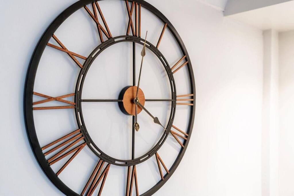 Um relógio de parede grande com números romanos e design minimalista.