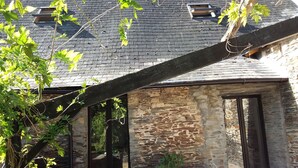 Un edificio de piedra con techo inclinado, una ventana pequeña y una puerta.