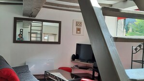 Una sala de estar moderna con un sofá, sillas rojas, una mesa de centro de vidrio y un televisor.