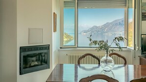 A dining area with a bay window overlooking a scenic lake and mountains. - Charming 4-bed Apartment -lake Views & Balconies (Oliveto Lario)