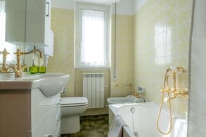 Appartement | Badkamer | Een bad/douchecombinatie, een diep bad, een haardroger, handdoeken