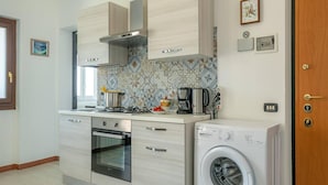 A compact kitchen with a built-in oven, a microwave, a gas stove, and a washing machine. - Charming 4-bed Apartment -lake Views & Balconies (Oliveto Lario)
