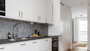A modern kitchen with white cabinets, a granite backsplash, and a stainless steel sink. - Modern Scandinavian Home in Stockholm (Stockholms län)