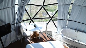 A modern room with a large window, a white bathtub, a small round table, and a chair. - Domo do Matto (Garanhuns)