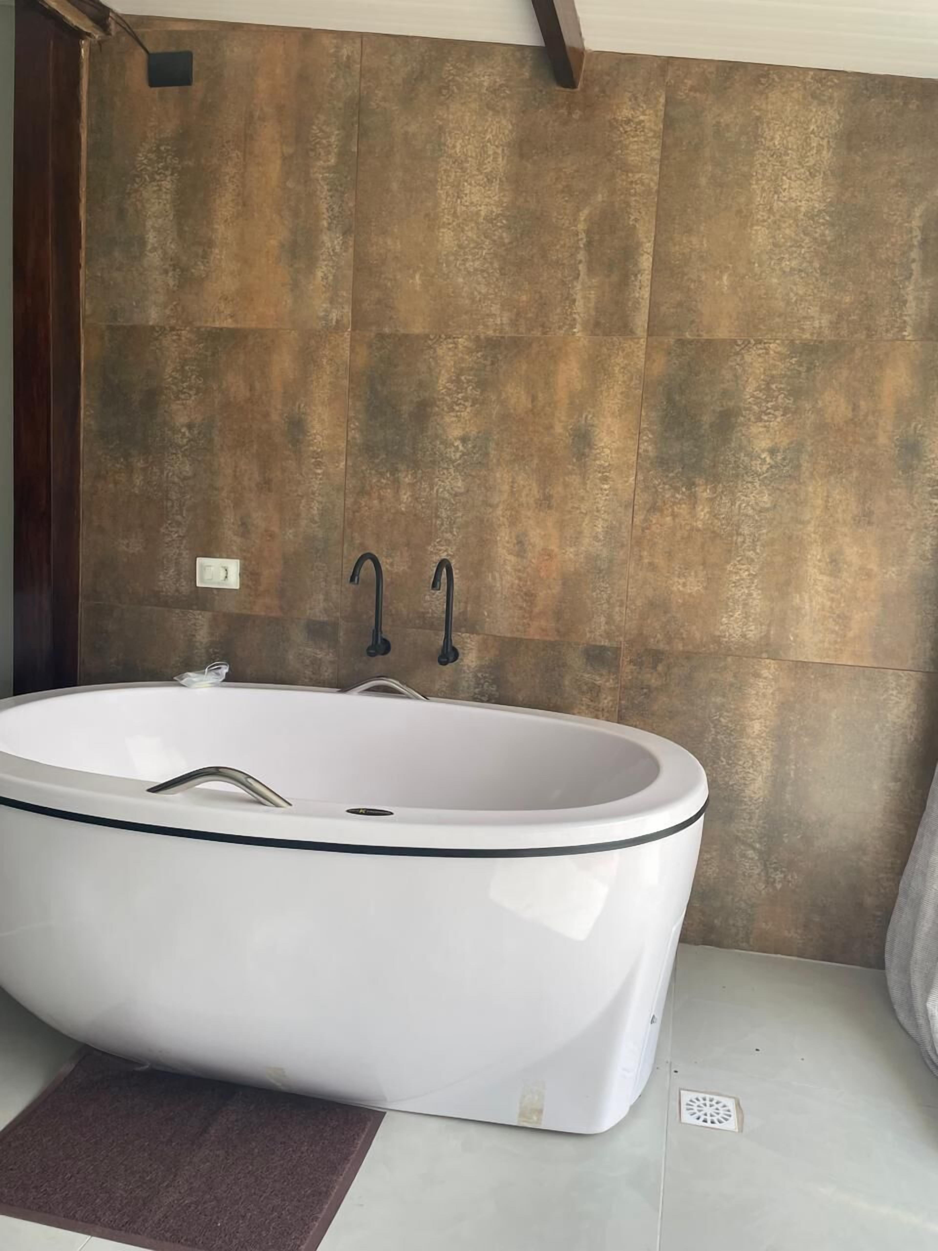 Ein modernes Badezimmer mit freistehender Badewanne, Handtuchhalter und Duschkopf.