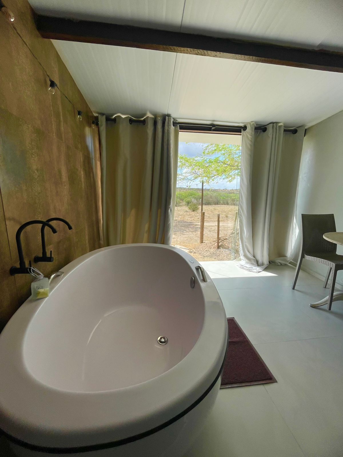 Un baño moderno con una bañera grande, una ducha y vistas a un paisaje árido por la ventana.