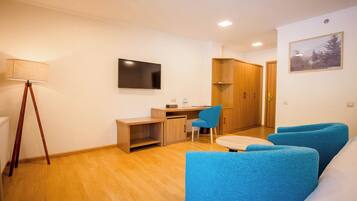 Una sala de estar moderna con piso de madera, un escritorio, una silla azul y un sofá.