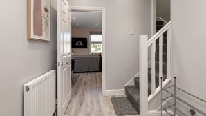 A hallway leading to a bedroom with a bed, a radiator, and a framed artwork on the wall.