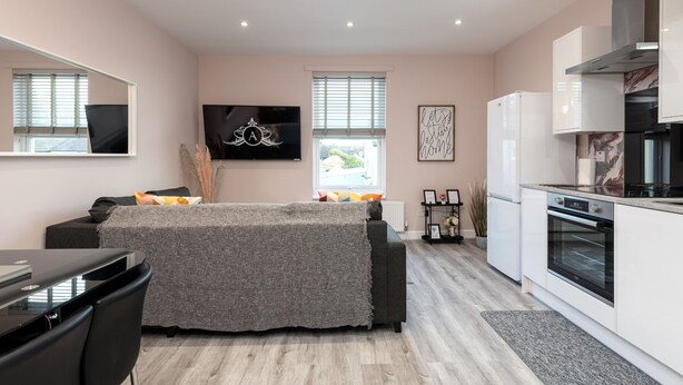 A modern apartment with a kitchenette, a dining area, and a living space with a TV and artwork.