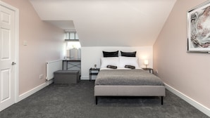 A bedroom with a bed, bedside tables, a radiator, and a window with blinds.