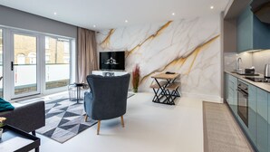 A modern living room with a TV, a dining area, and a kitchen.