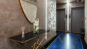 A modern hotel lobby with a glass table, a vase with flowers, a mirror, and a blue floor.