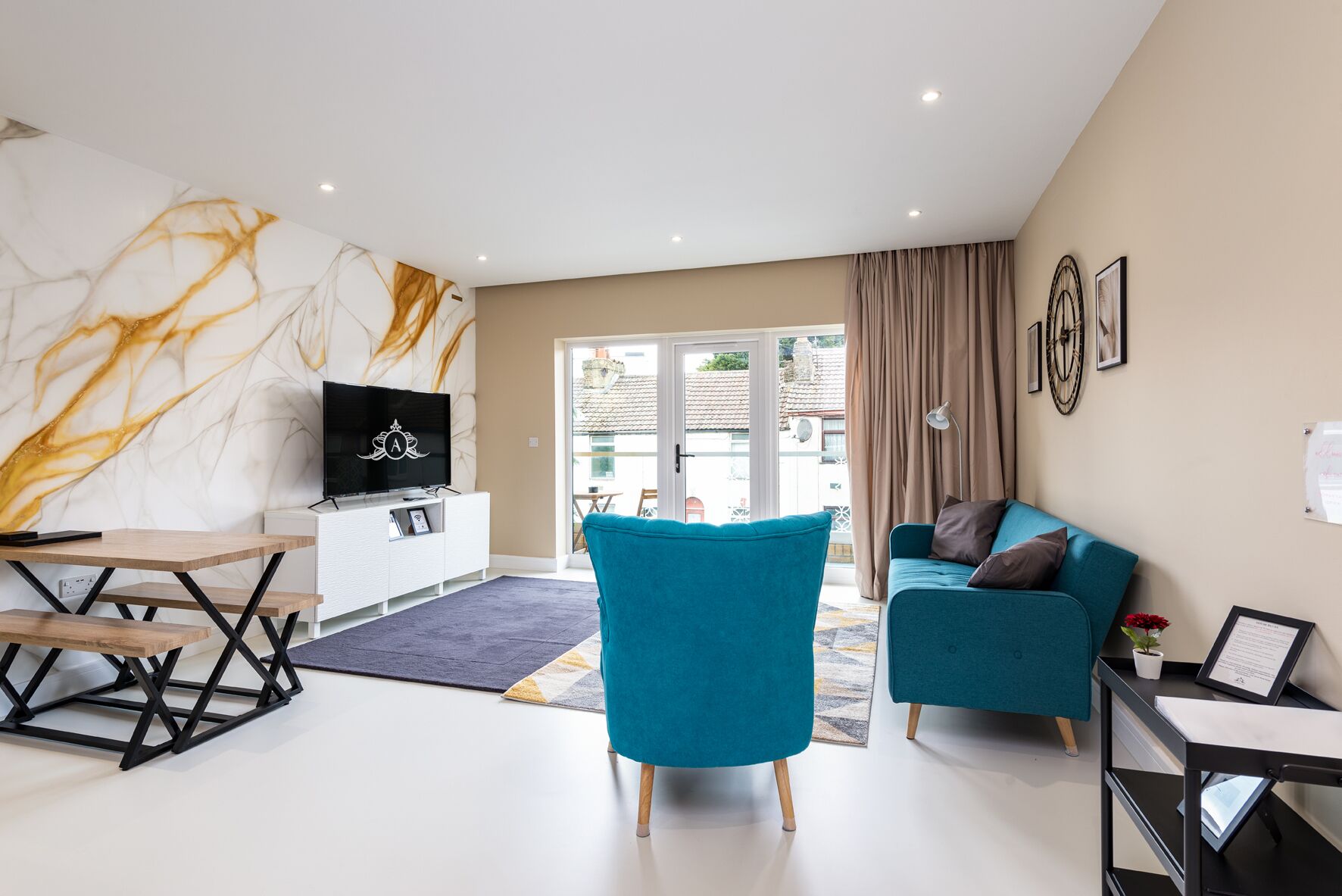A modern living room with a flat-screen TV, a teal sofa, and a coffee table.