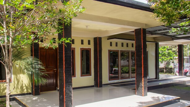 A modern building with a covered entrance, large windows, and a tiled floor. - OYO Life 93409 Anugrah House (Mataram)