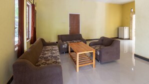 A living room with two sofas, a wooden coffee table, and a refrigerator. - OYO Life 93409 Anugrah House (Mataram)