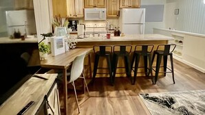 Une cuisine moderne avec des meubles en bois, un îlot central doté de tabourets et des luminaires suspendus.