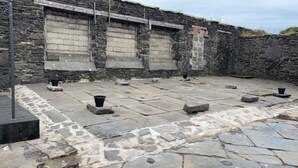 A courtyard with stone flooring and a stone wall.