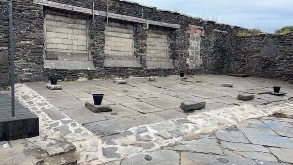 A courtyard with stone flooring and a stone wall.