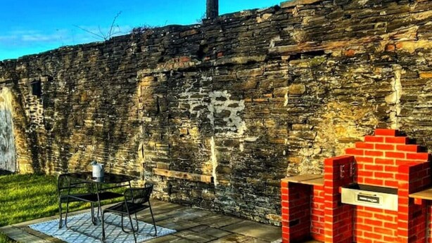 A stone wall with graffiti, a metal table with chairs, and a red brick structure.