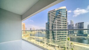 Ein Hochhaus mit "DAMAC"-Beschriftung, Blick auf einen Fluss und moderner Architektur.