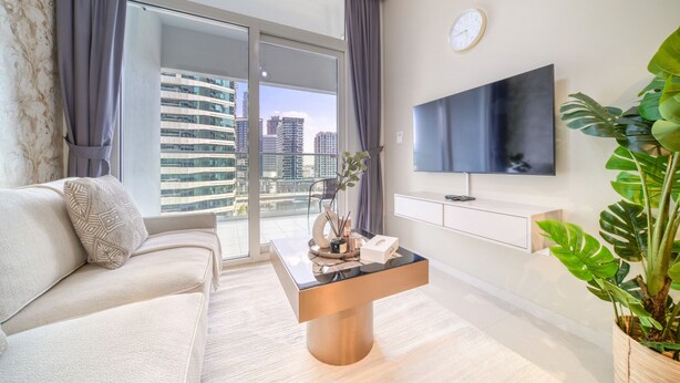 Ein modernes Wohnzimmer mit Sofa, Couchtisch, Fernseher und Balkon mit Blick auf die Stadt.