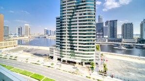Ein modernes Hochhaus-Hotel mit einem gut sichtbaren "DAMAC"-Schild, gelegen am Wasserufer mit Blick auf die Stadtlandschaft und einen Fluss.