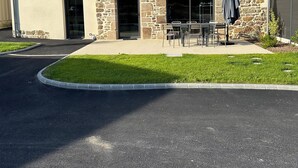 A two-story house with a stone facade, a garage door, and a small patio with outdoor seating.